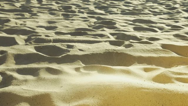 Man sieving sand with his hand. Barefoot human playing in desert. Senseless act and loneliness concept. Close-up. Side view.