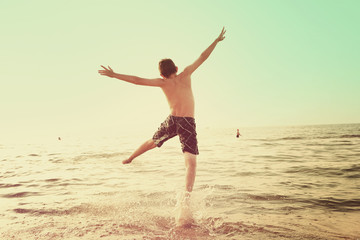 Fototapeta na wymiar Boy jumping into the waves of a lake. Instagram effect.