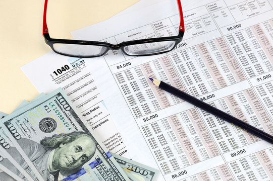 tax calculation forms with pencil, eye glasses and USD dollar cash