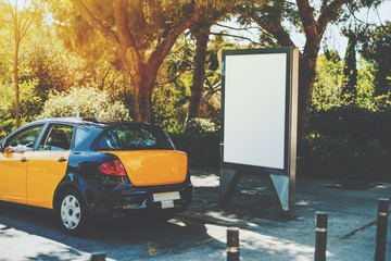 Blank billboard with copy space for your text message near yellow taxi, public information board in...