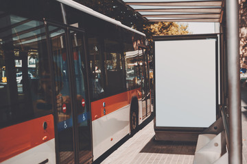 White billboard with copy space area for your text message or promotional content, public information board near red bus, city bus stop with blank empty mock up banner for your advertising
