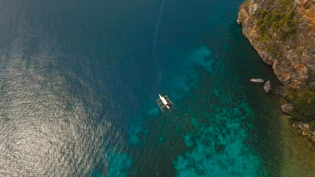 Aerial view of motor boat in sea. Aerial image of motorboat floating in a turquoise blue sea water. Sea landscape with wake of small fast motorboat. Tropical landscape. Philippines, El Nido. 4K video