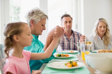 Multi-generation family praying before having meal