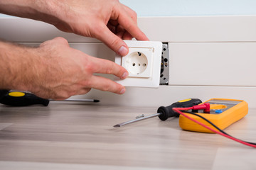 Person's Hand Installing Socket On Wall