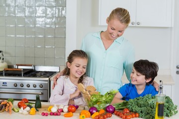 Mother and kids preparing a salad in kitchen