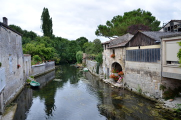Fototapeta na wymiar small river flowing between buildings in Pons, France. One of the cleanest in Europe.