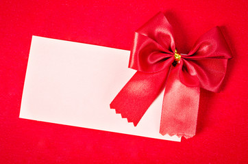 Blank card with red ribbon on red background.