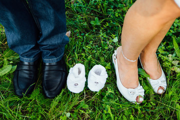 Pair of little shoes between feet  future parents