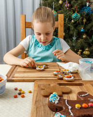 Little girl decorating of christmas gingerbread cookie