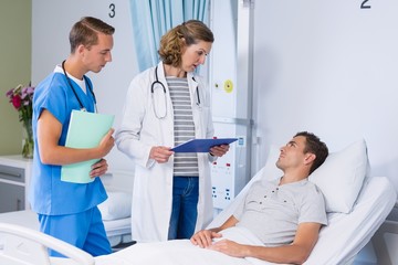 Fototapeta premium Doctors talking to patient in hospital bed