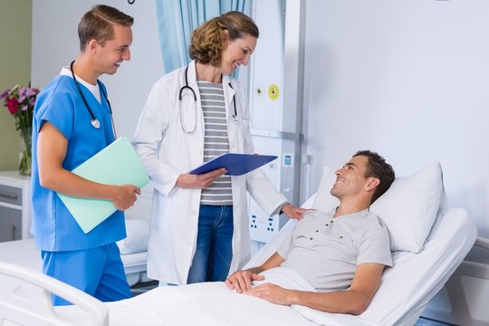 Doctors talking to patient in hospital bed