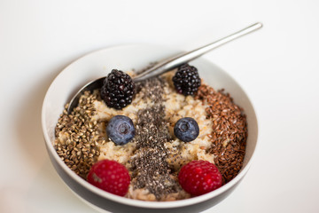 Oatmeal in a bowl, deep plate with berry, berries. Rassberry, blueberry, blackberry. Healthy breakfast. Seeds. Flax seed, hemp seed, chea seed