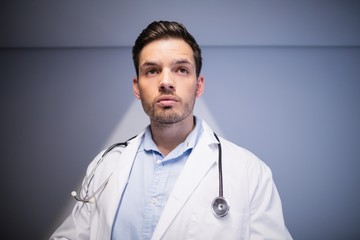 Thoughtful doctor standing in corridor