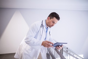 Doctor using digital tablet in corridor