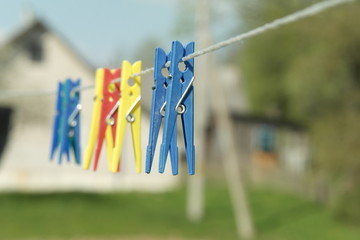 Colorful clothes pins on rope. Art concept on blurred country house background