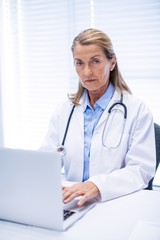 Portrait of female doctor using laptop