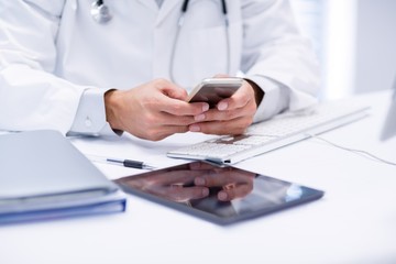 Mid section of doctor using mobile phone - Powered by Adobe