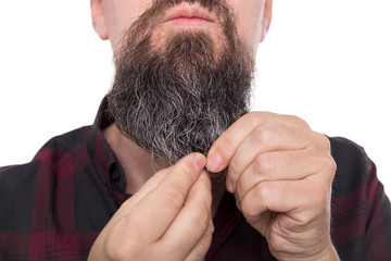 Mann massiert Bartöl in seinen Vollbart, formt seinen Bart