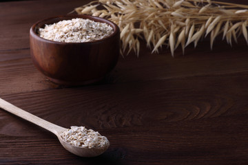 Tha flakes of oat in wooden plate and spoon