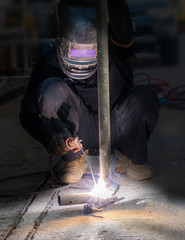 Man with welding helmet welding steel