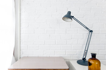 Table and desk lamp side the window on white brick wall background