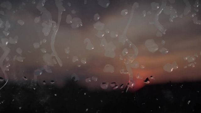 Nasse Fensterscheibe mit Regentropfen mit Wolken im Hintergrund
