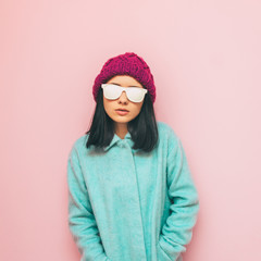 Lady in winter clothing: oversize mint coat and purple hat on pink wall. Fashion of 90's. Pastel and minimalism.