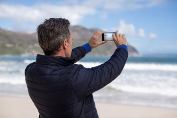 Mature man photographing scenery using cell phone