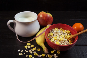 Breakfast with muesli, fruits and milk on black background
