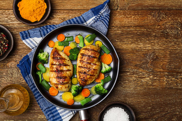 Grilled chicken breast with vegetables in a pan.