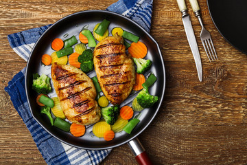 Grilled chicken breast with vegetables in a pan.