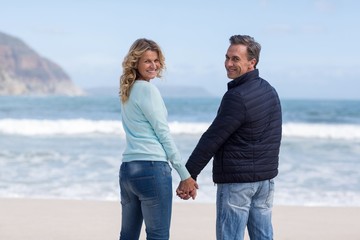 Portrait of couple standing with holding hands on the beach