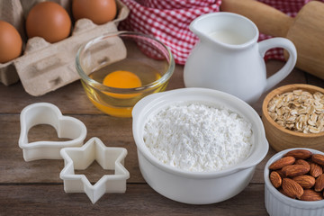Fototapeta na wymiar Baking ingredients flour, egg, milk, almonds, oat on wooden table