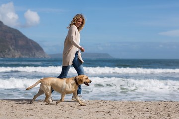 Woman walking with her dog on the beach - Powered by Adobe