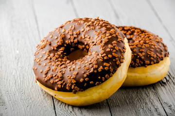 Donuts with chocolate on white wooden background, top view.