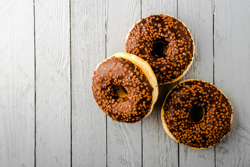 Donuts with chocolate on white wooden background, top view.