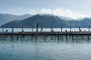 Fototapeta na wymiar Wooden jetty in the sea with mountain and forest background
