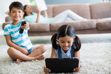 Boy watching tv while girl using digital tablet