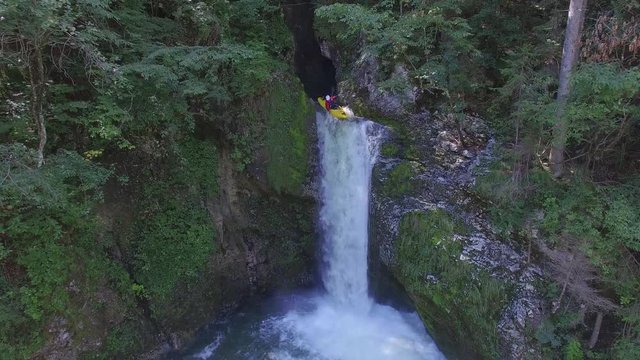 AERIAL: Extreme pro kayaker running whitewater waterfall in beautiful ravine