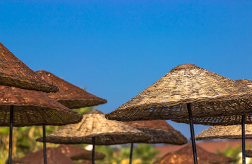 Straw beach umbrellas and blue sky background. Holiday summer vacation concept. No People