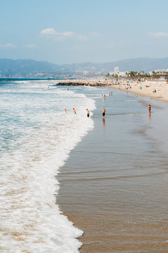 Pacific ocean coastline in Los Angeles USA. People walking at the beach. Ocean waves and foam.