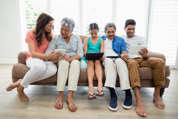Fototapeta na wymiar Multi-generation family using digital tablet in living room