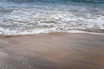 Soft wave of blue ocean on sandy beach. Background.