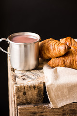 Heap of freshly baked croissants on linen cloth, aluminum mug with hot cocoa on vintage wood box, cozy atmosphere, morning,breakfast,poster template mockup for cafe or restaurant