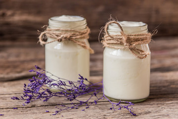 Yogurt in jar on the wooden table with purple dried plant