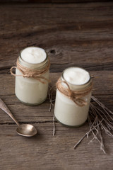 Yogurt in jars on the wooden table with dried plant