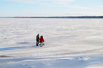 young family with a small child walking on the ice of the sea in frosty and Sunny winter day