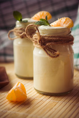 Fresh organig natural white yogurt in glass jars with tangerine