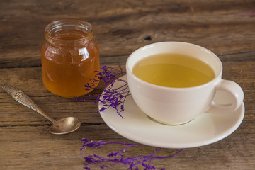 Cup of tea with honey in jar on the wooden table