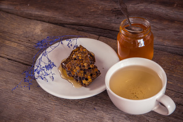 Honeycombs and honey in jar and green tea on wooden background